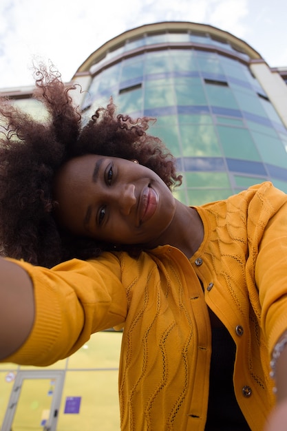 Una donna afroamericana felice e giovane prende un selfie, primo piano