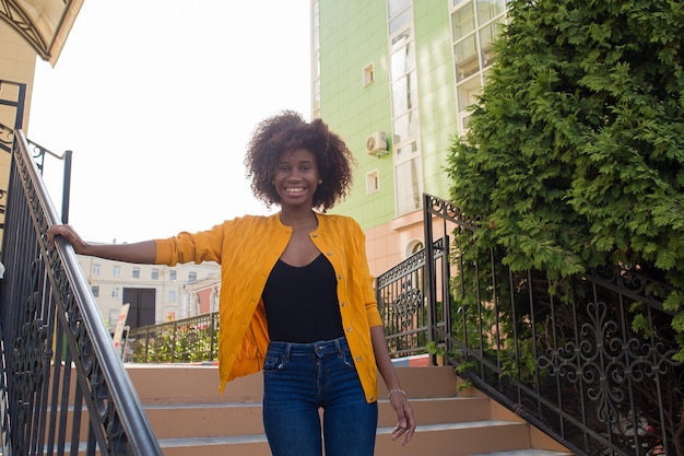 A happy and young African American woman walks down the street