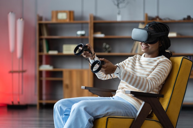 写真 仮想現実のゴーグルを身に着け自宅でビデオゲームをしている幸せな若いアフリカ系アメリカ人女性