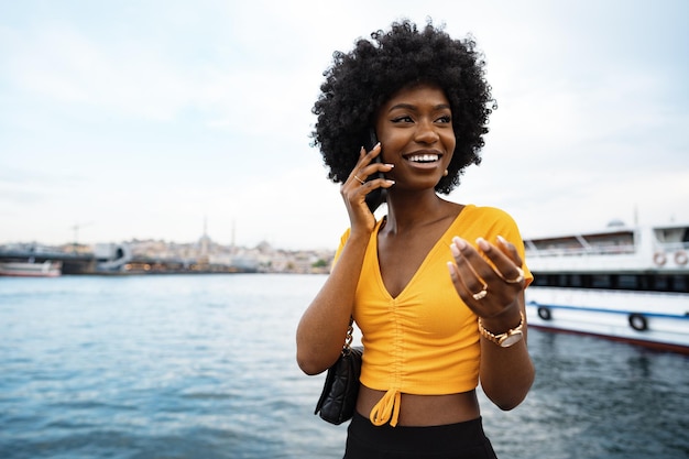 市内で携帯電話で話している幸せな若いアフリカ系アメリカ人の若い女性