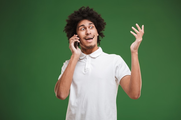 Happy young african curly man talking by mobile phone.