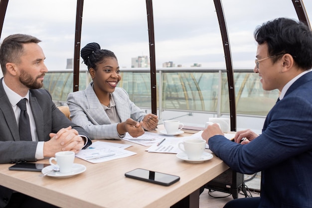 Happy young african female economist interacting with chinese colleague