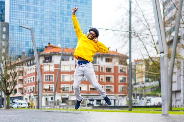 Photo happy young african man jumping while listening to music