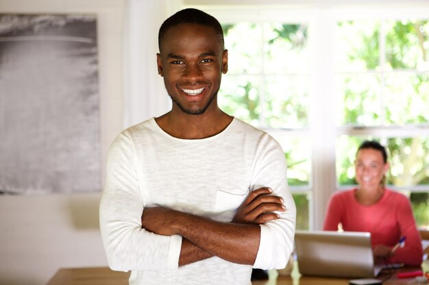 Happy young african man standing with his arms crossed