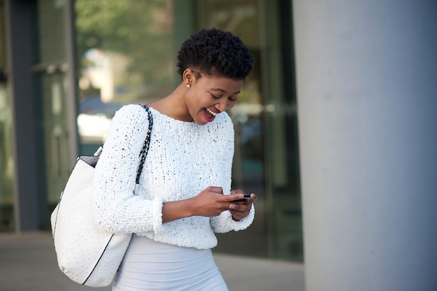 Happy young african woman reading text on cell phone