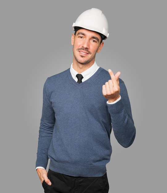 Happy young architect making a money gesture with his hand