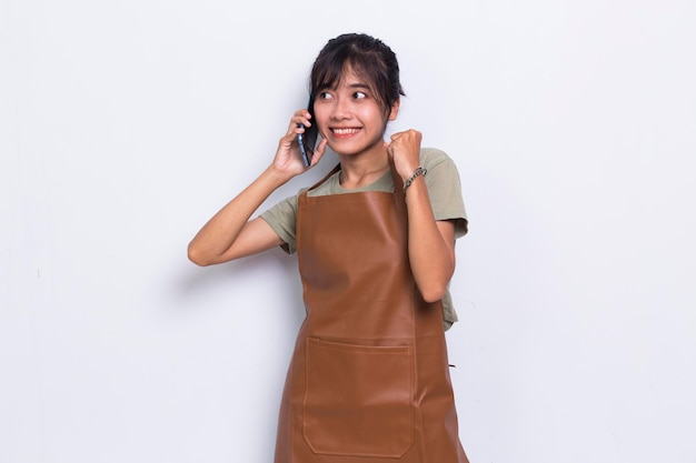 Happy young asian barista waitress using mobile smartphone isolated on white background