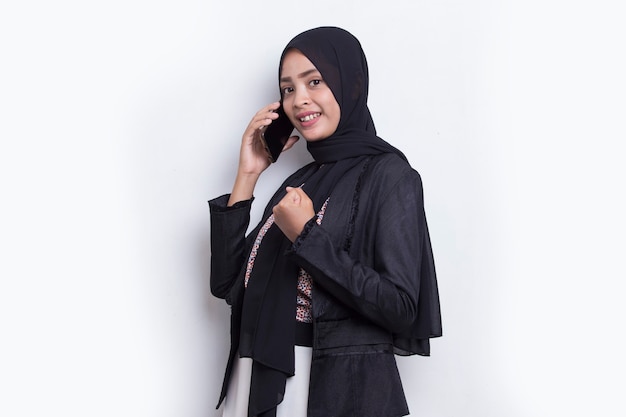 흰색 배경에 고립 된 휴대 전화를 사용 하 여 행복 한 젊은 아시아 아름 다운 이슬람 여자