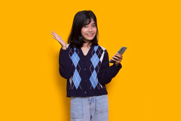 happy young asian beautiful woman using mobile phone isolated on yellow background