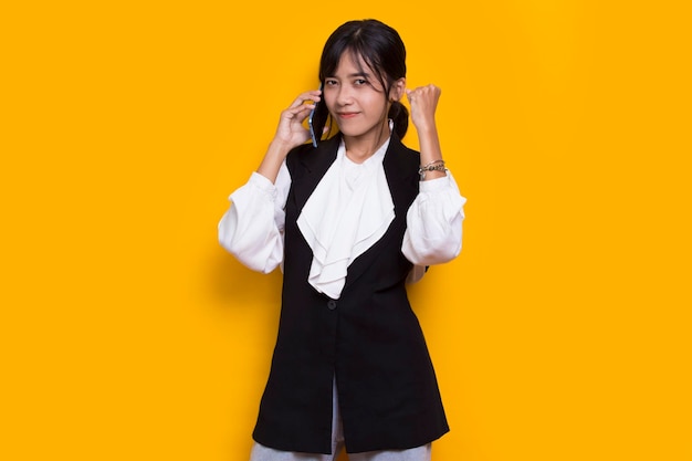 Felice giovane bella donna asiatica utilizzando il telefono cellulare isolato su sfondo giallo