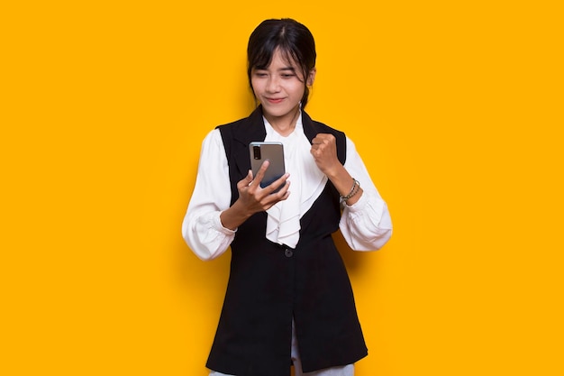 노란색 배경에 고립 된 휴대 전화를 사용 하 여 행복 한 젊은 아시아 아름 다운 여자