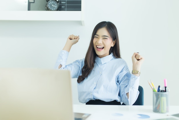 La giovane donna asiatica felice di affari ha finito il suo lavoro nel luogo di lavoro.