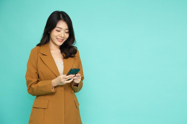 Happy young Asian business woman using mobile phone isolated on green background