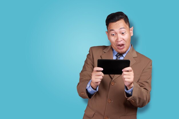 happy young Asian businessman playing on his tablet surfing browsing good news online games