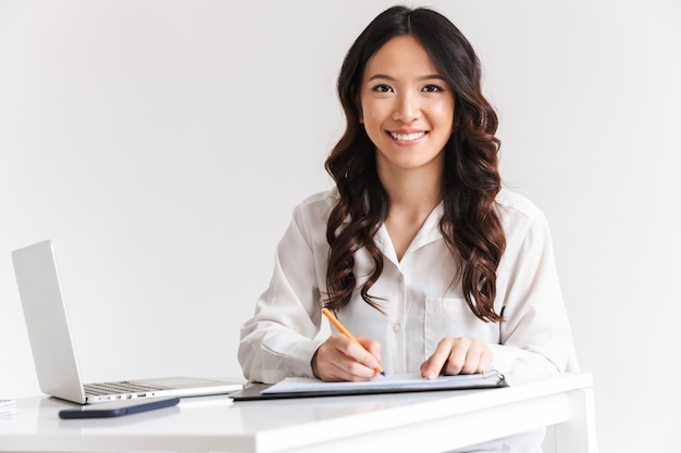 Happy young asian businesswoman taking notes