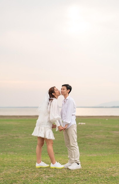 결혼과 결혼을 축하할 준비가 된 신부와 신랑 옷을 입은 행복한 젊은 아시아 커플