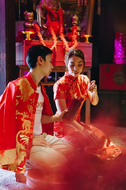 Foto una felice giovane coppia asiatica in abiti tradizionali cinesi che prega al tempio
