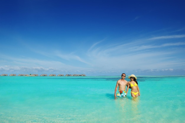 Молодая счастливая азиатская пара наслаждается летом и на красивом белом песчаном пляже