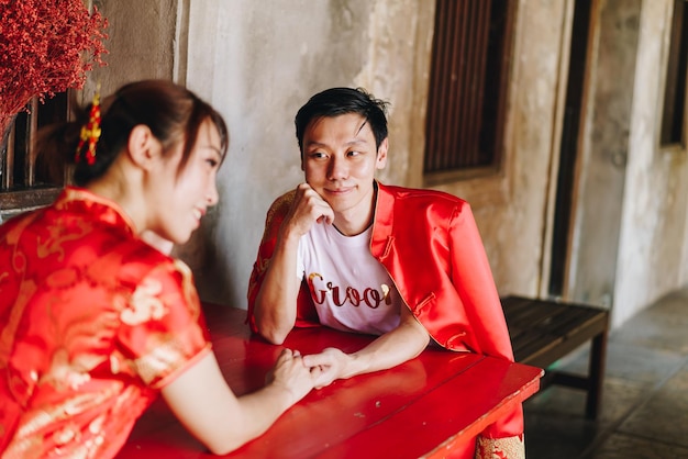 중국 전통 드레스를 입은 행복한 젊은 아시아 커플 사랑 - 빨간색은 중국에서의 결혼식을 포함한 전통 축제의 주요 색상입니다.