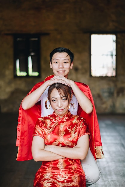 Happy young asian couple love in chinese traditional dresses -\
red is the main color of the traditional festive that including\
wedding in china.