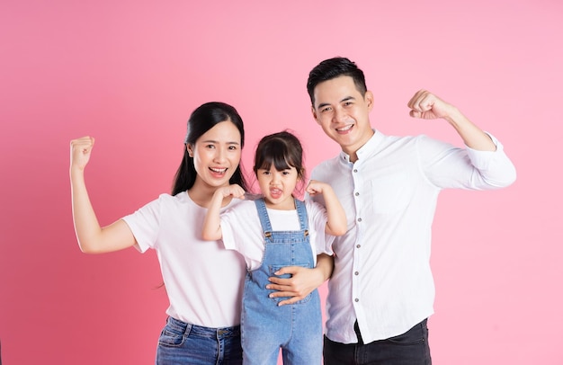 Happy young asian family image isolated on pink background