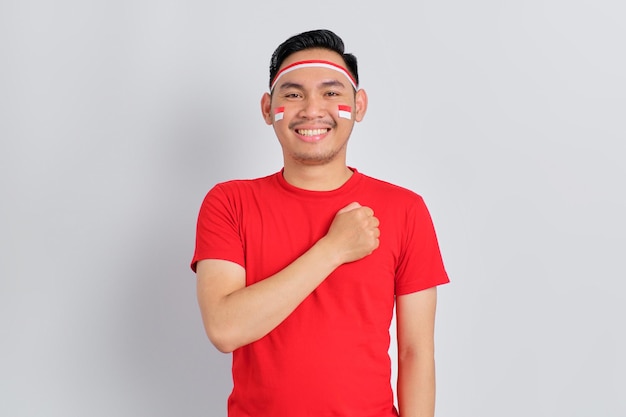 Happy young Asian man celebrate Indonesian independence day with hand on chest feeling proud isolated on white background