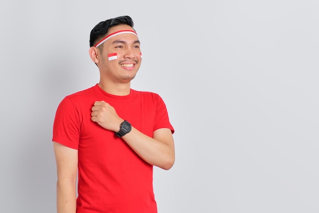 Happy young Asian man celebrate Indonesian independence day with hand on chest feeling proud isolated on white background