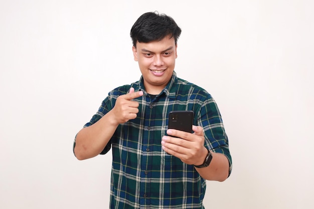 Happy young asian man pointing on his cell phone Isolated on white