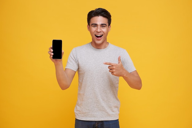 Happy young Asian man showing and pointing at blank screen smartphone great mobile offer