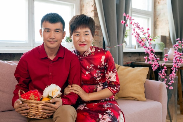 Happy young asian man and woman with basket of flowers and postcard