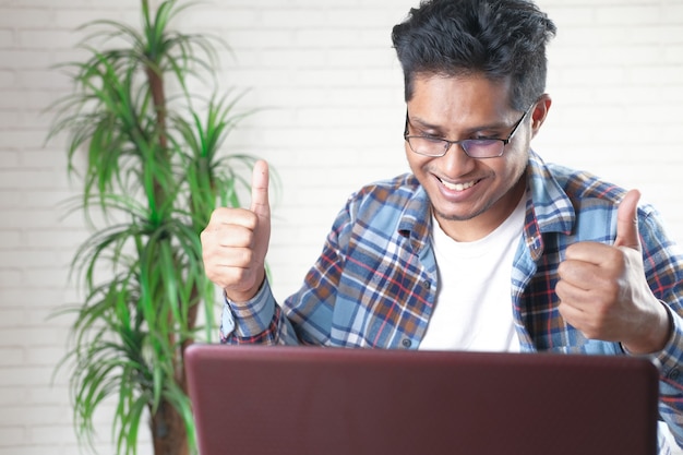 Happy young asian man working on laptop with copy space