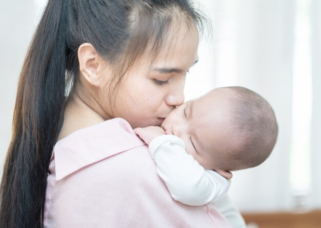 Happy young asian mother smiling hugging holding newborn baby in her arms