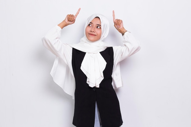 Felice giovane donna d'affari musulmana asiatica che punta con le dita in direzioni diverse su bianco