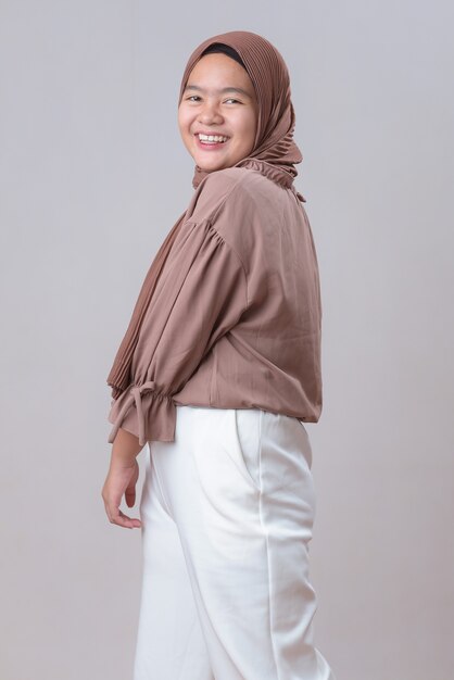 Happy Young Asian muslim model woman in hijab smiling posing isolated on gray background