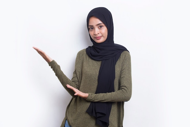 Happy young asian muslim woman pointing with fingers to different directions isolated on white