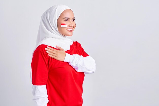 Happy young Asian muslim woman in red white tshirt greeting to celebrating indonesian independence day on 17 august isolated on white background