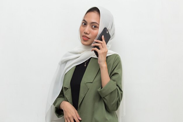 Photo happy young asian muslim woman using mobile phone