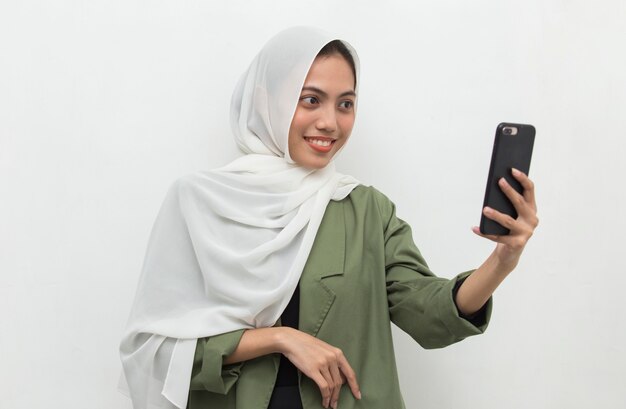 Happy young asian muslim woman using mobile phone