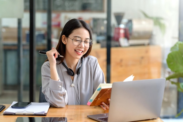 Happy young asian student woman wearing headphones looking at\
webcam looking at camera during virtual meeting or video call\
talk