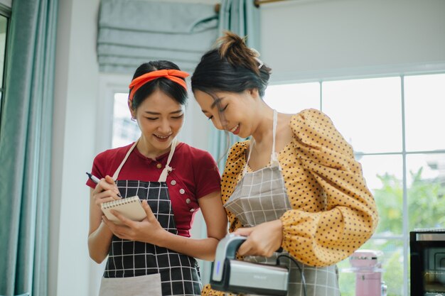 エプロン、笑顔と料理で幸せな若いアジアの女性。