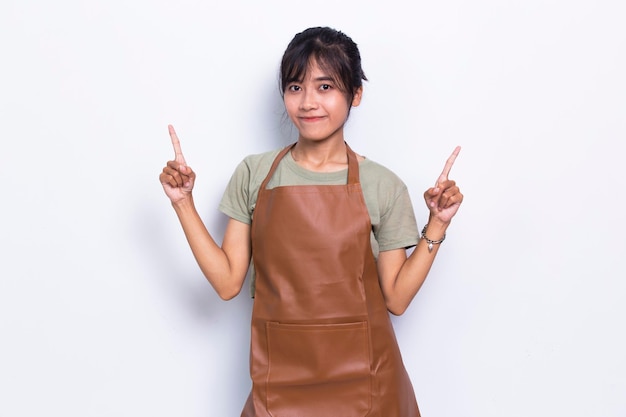 Счастливая молодая азиатская женщина-бариста-официантка, указывающая пальцами в разные стороны на белом