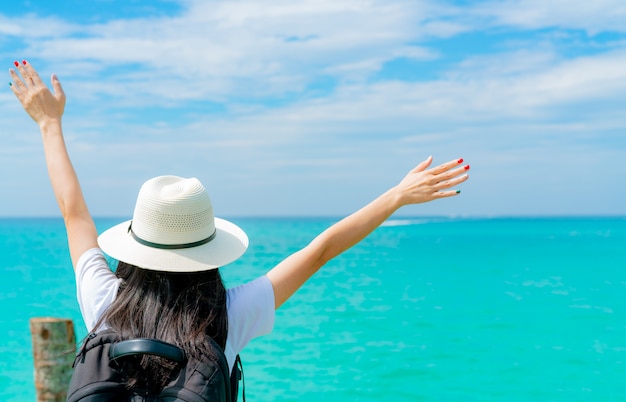 Happy young Asian woman in casual style fashion with straw hat and backpack. Relax and enjoy holiday at tropical paradise beach. Girl in summer vacation. Summer vibes.