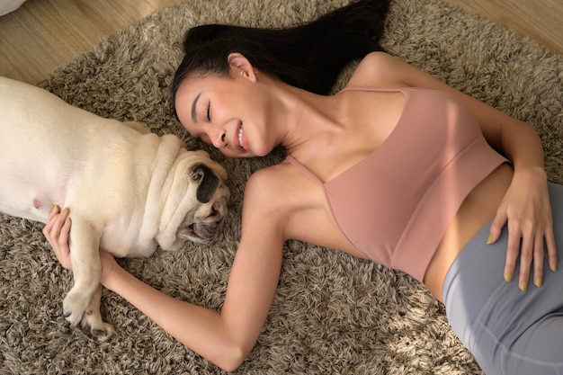 Happy young asian woman cuddling and spending time with cute dog in living room