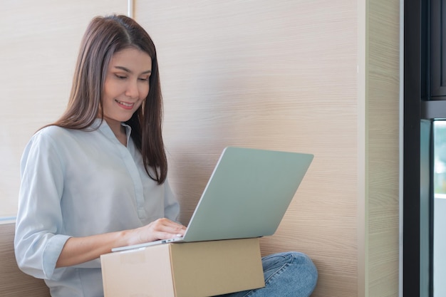 Happy young Asian woman entrepreneur Smile for sales success after checking order from online store