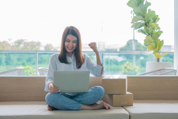 Happy young Asian woman entrepreneur Smile for sales success after checking order