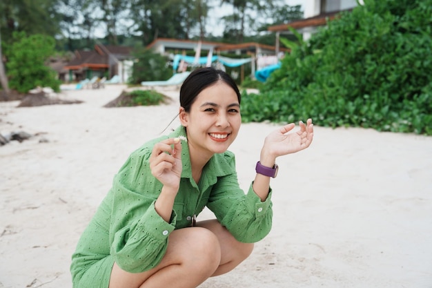 Happy young asian woman in green clothes enjoying with crab on the beach in tropical sea at vacation