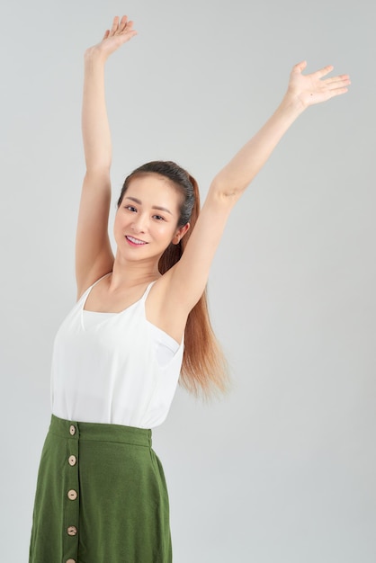 Happy young Asian woman hands up in the air over white background