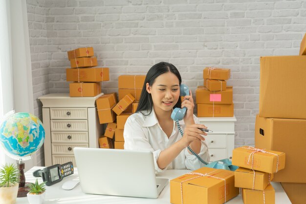 Felice giovane donna asiatica ha un problemi di piccole imprese per lo shopping online