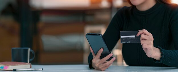 Foto felice giovane donna asiatica in possesso di carta di credito e utilizzando smartphone per lo shopping online con il pagamento su internet banking