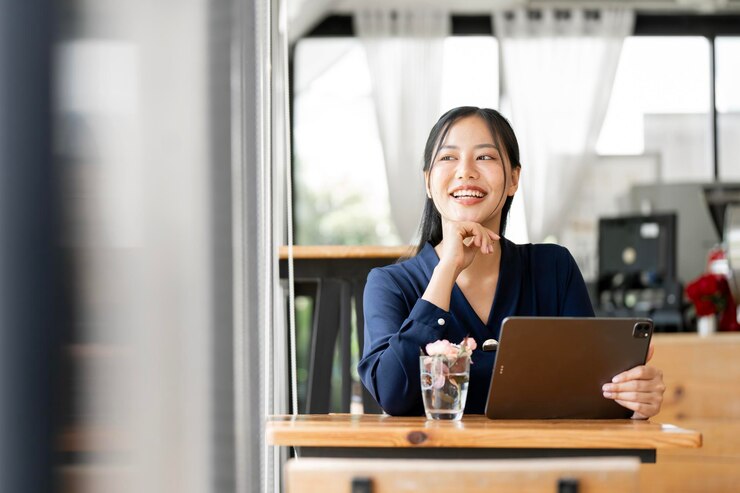 Photo happy young asian woman looking away professional business services using digital tablet sits at cafe portrait